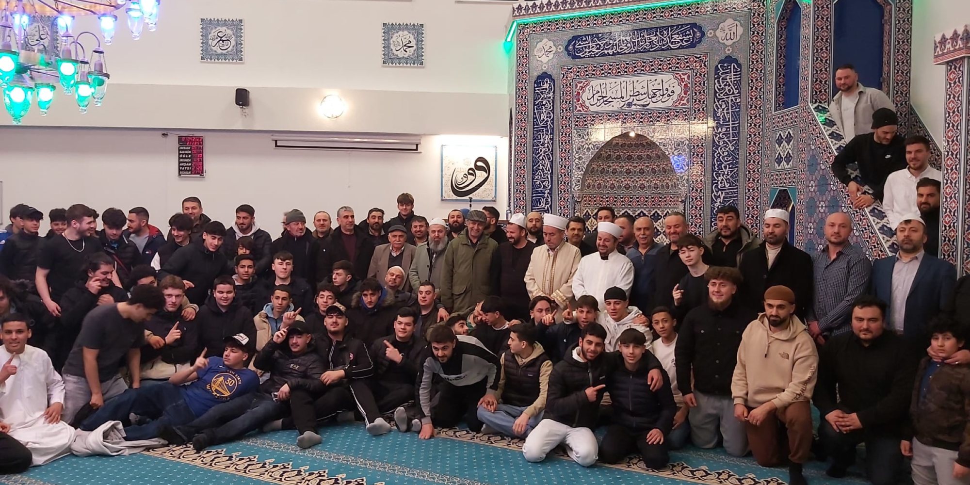 Große Jugendgruppe mit Imamen im Gebetsraum einer Moschee
