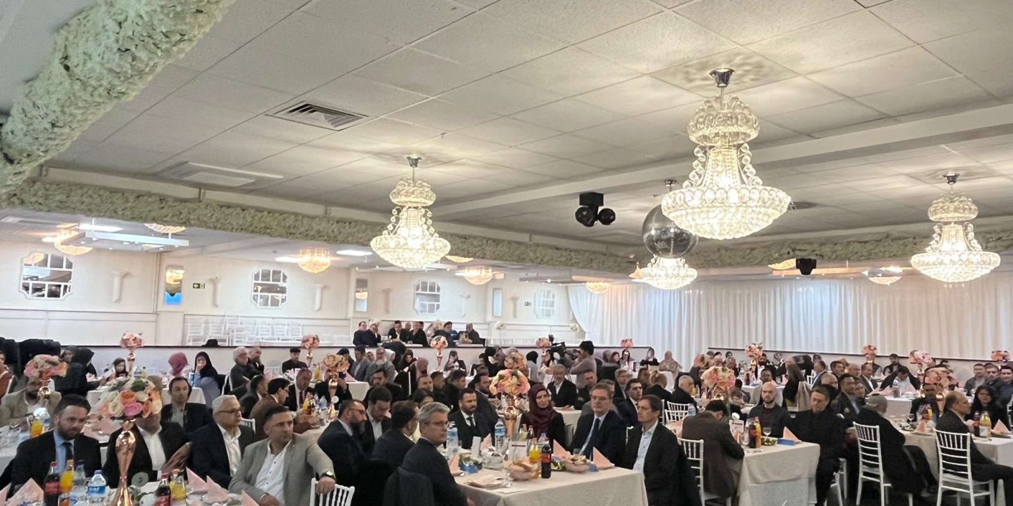 Festempfang mit Gästen an gedeckten Tischen in einem Saal mit Kronleuchtern